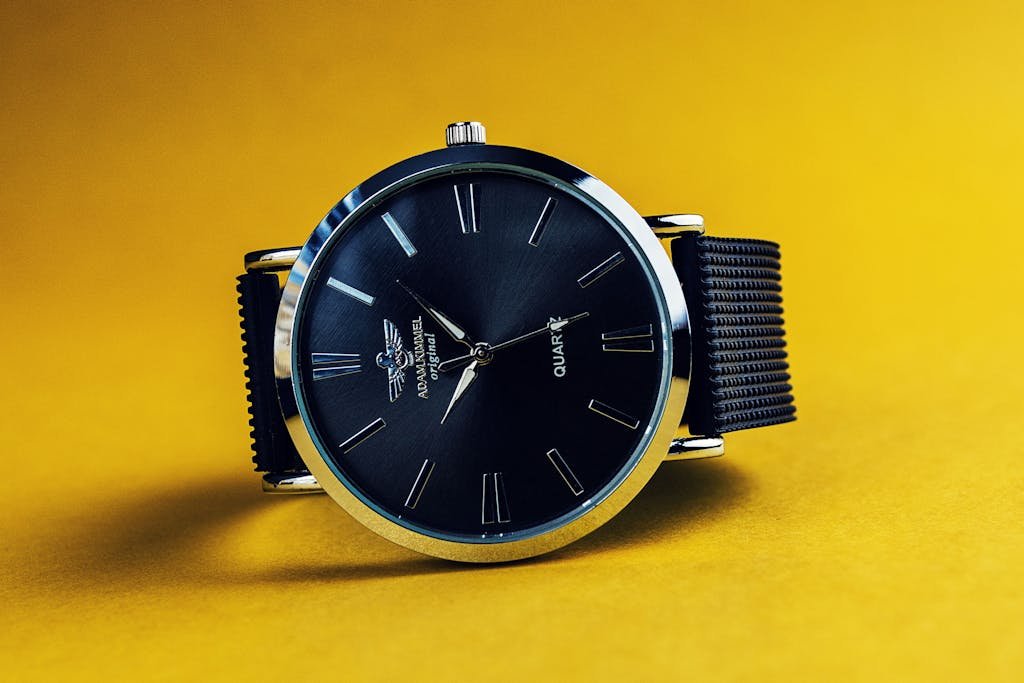 Stylish black analog wristwatch with a black strap on a vibrant yellow background.